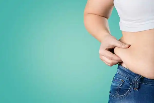 Image of woman pinching her love handles to show weight gain Henley In Arden
